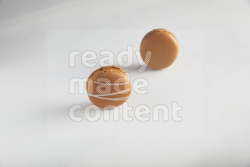 45º Shot of of two assorted Brown Irish Cream, and Brown Maple Taffy macarons  on white background
