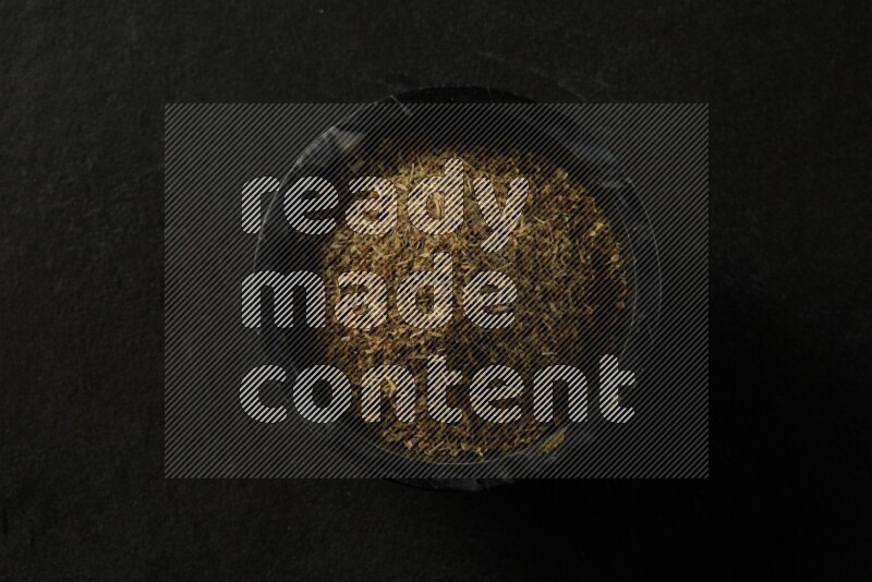 black pottery round sauce bowl filled with herbs on grey textured countertop