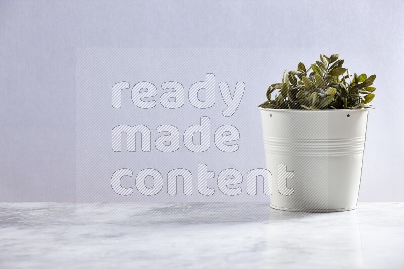 Green artificial plant in white pot on grey marble background