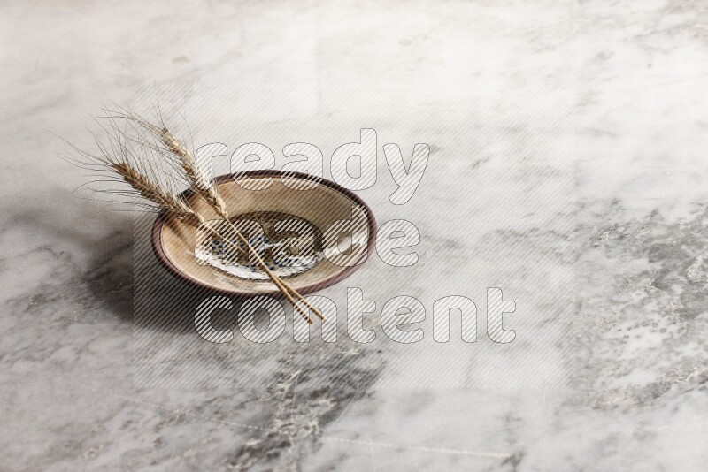 Wheat stalks on decorative pottery plate on grey marble background