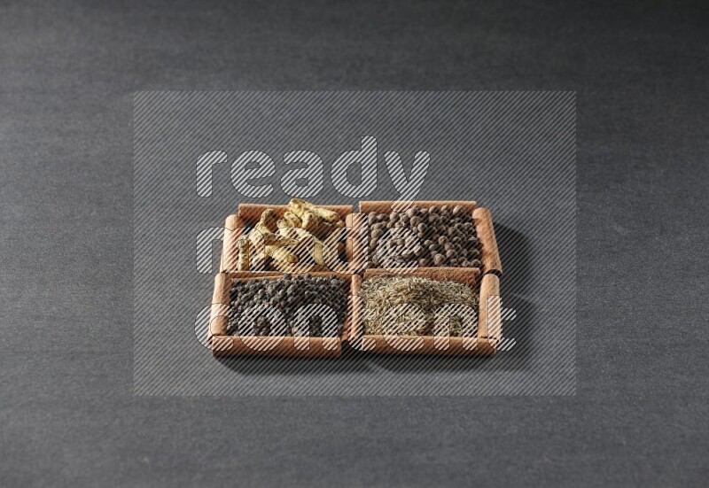 4 مربعات من عيدان القرفة ممتلئة بحبوب الفلفل الأسود والكمون وبهار الفلفل الحلو وأصابع الكركم على أرضية سوداء