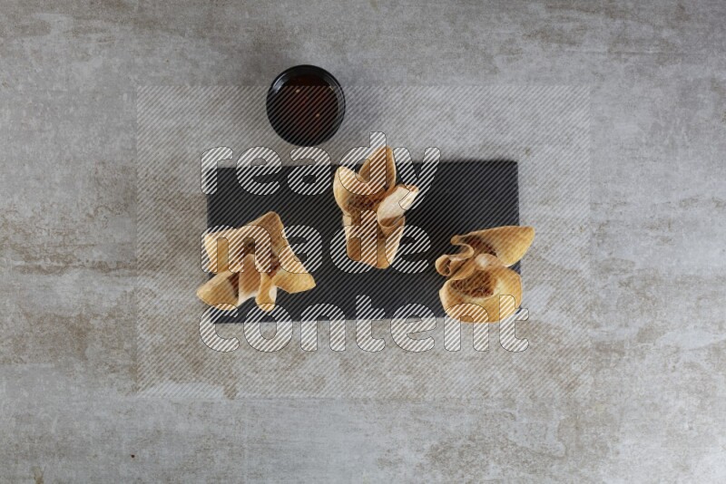 wonton cups with soy sauce ramkin on rectangle slate on grey textured counter top