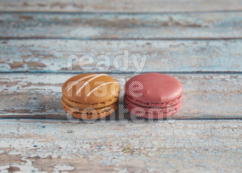45º Shot of of two assorted Brown Irish Cream, and Pink Raspberry macarons on light blue background