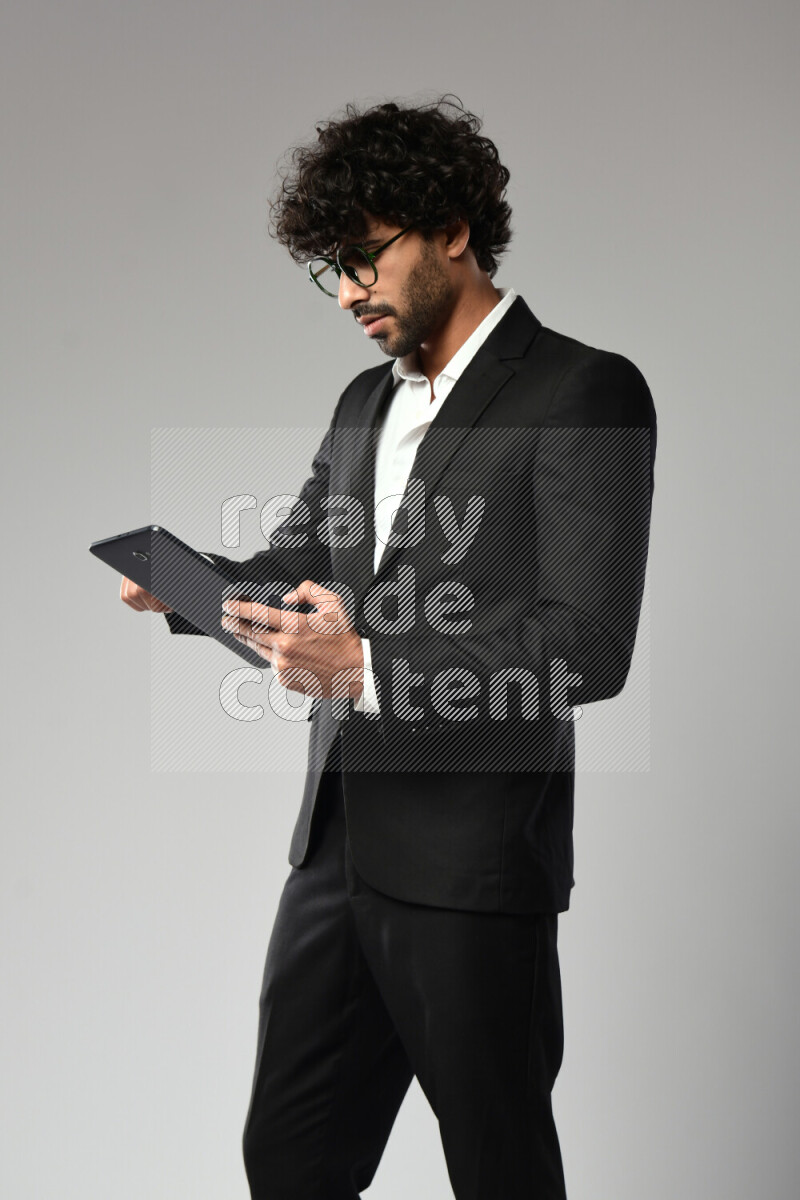 A man wearing formal standing and browsing on a tablet on white background