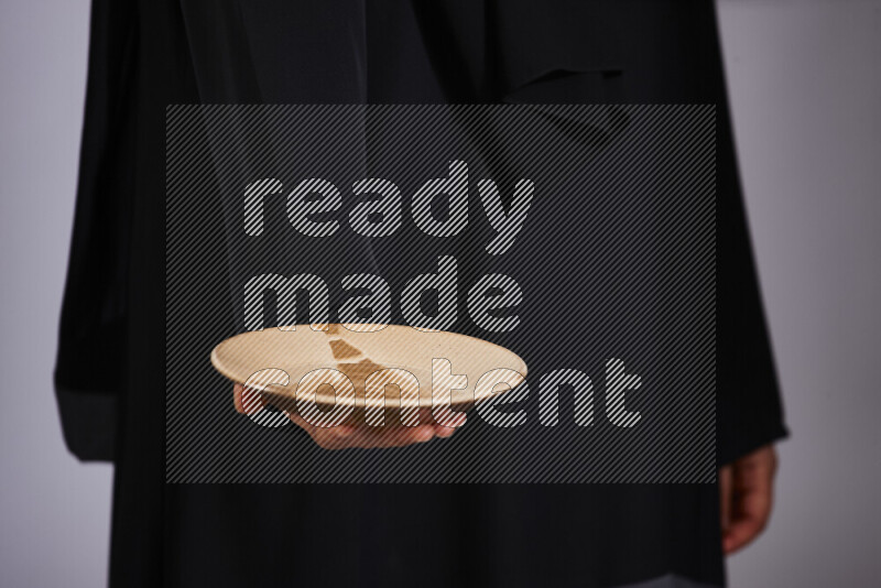 A woman in black abaya holding different pottery essentials in different positions