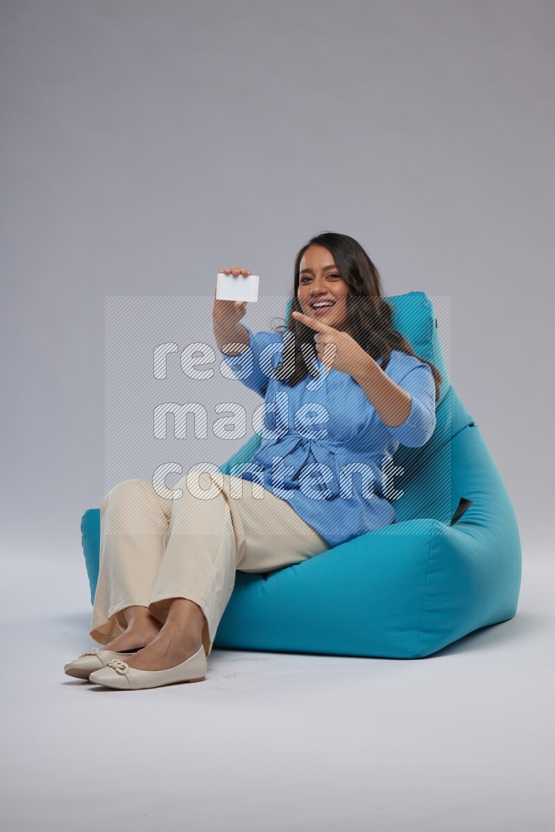 A woman sitting on a blue beanbag and holding ATM card