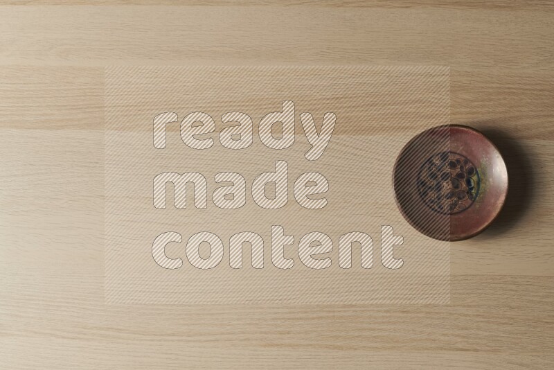 A decorative pottery plate on light wooden background