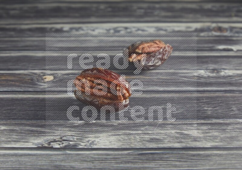 two pecan stuffed madjoul date on a wooden grey background