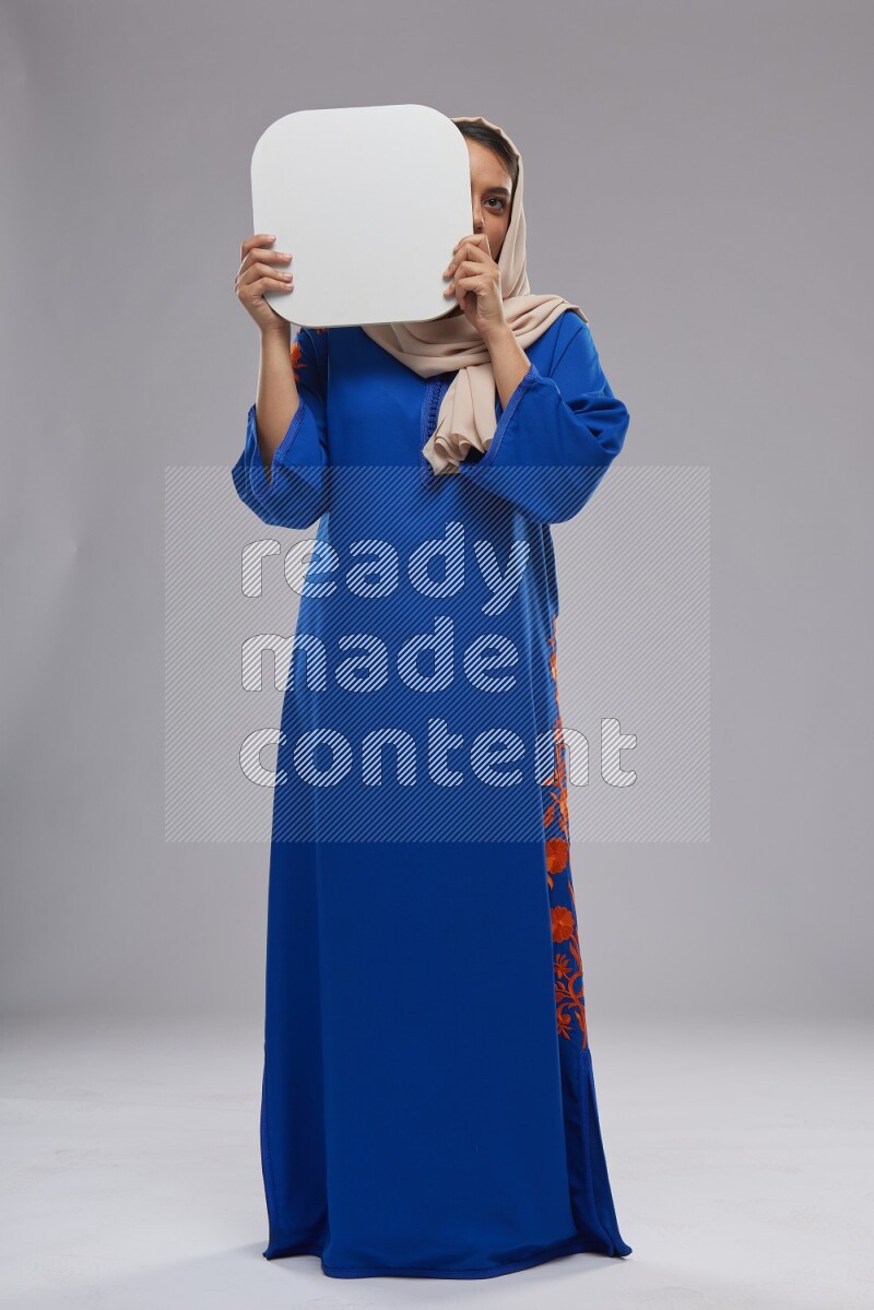 A Saudi woman standing wearing Jalabeya holding a social media sign