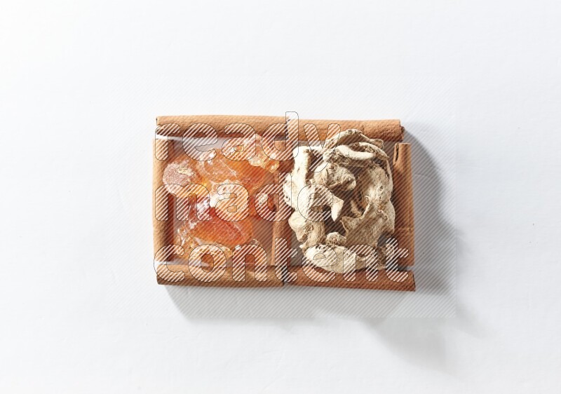 مربعان من أعواد القرفة ممتلئان بالزنجبيل المجفف والصمغ العربي علي خلفية بيضاء