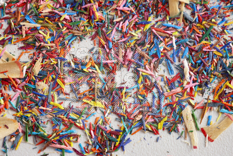 This image showcases a vibrant multicolored pencil shavings scattered on grey background