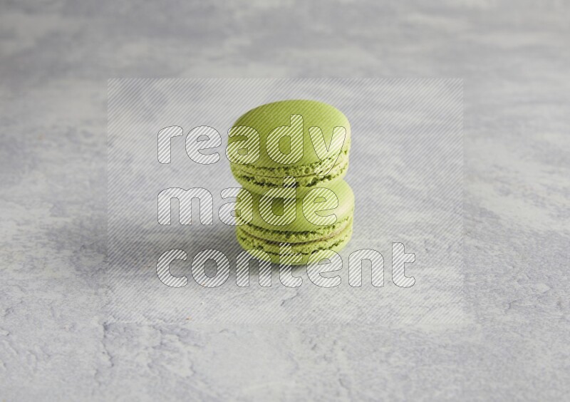 45º Shot of two Green Pistachio macarons  on white  marble background