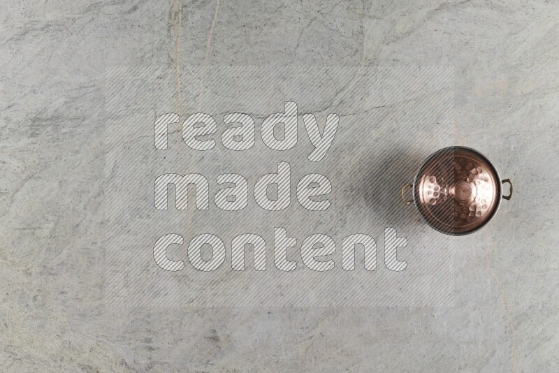 A small copper pot on grey marble background