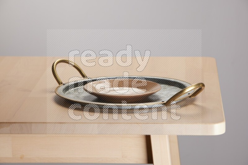 multicolored plate placed on a rounded stainless steel tray with golden handels on the edge of wooden table