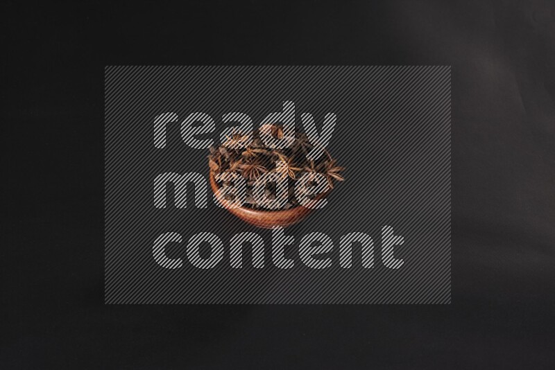 يانسون نجمي في وعاء خشبي علي خلفية سوداء