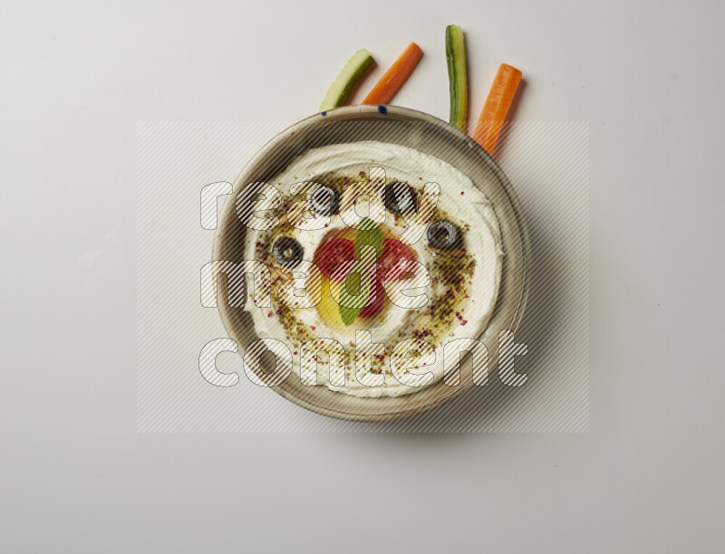 Lebnah garnished with cherry tomato, mint, olives & pine nuts in a grey pottery plate on a white background