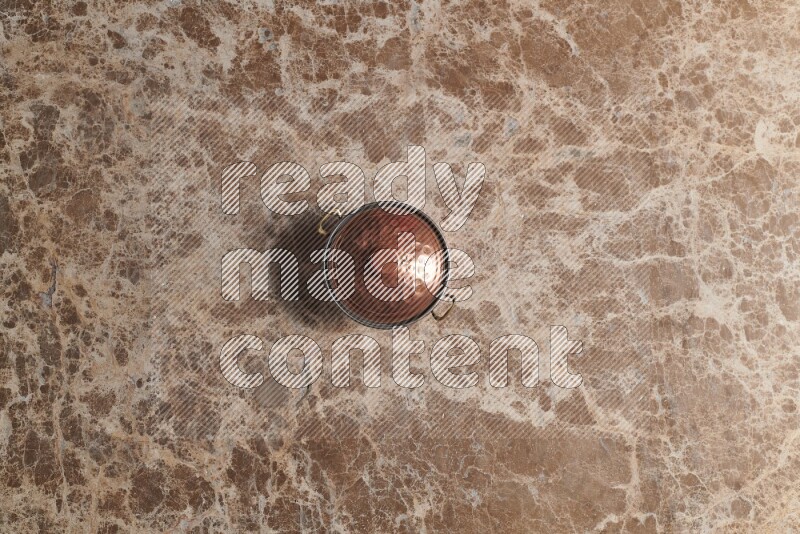 A small copper pot on beige marble background