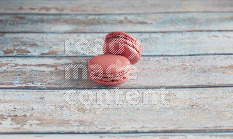 45º Shot of two Pink Raspberry macarons on light blue wooden background