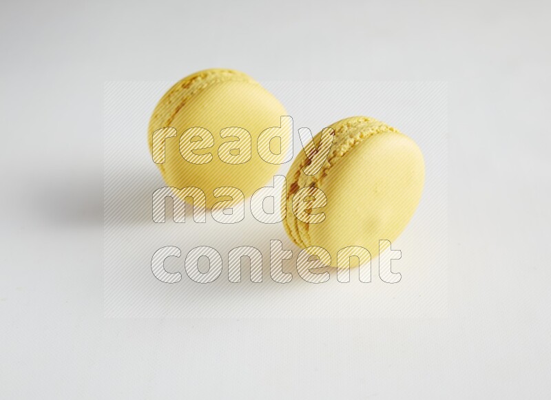 45º Shot of two Yellow Lemon macarons on white background