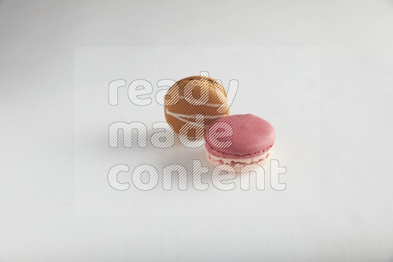 45º Shot of of two assorted Brown Irish Cream, and Pink Litchi Raspberry macarons on white background