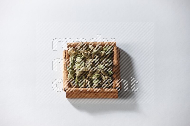 A single square of cinnamon sticks full of cardamom on white flooring