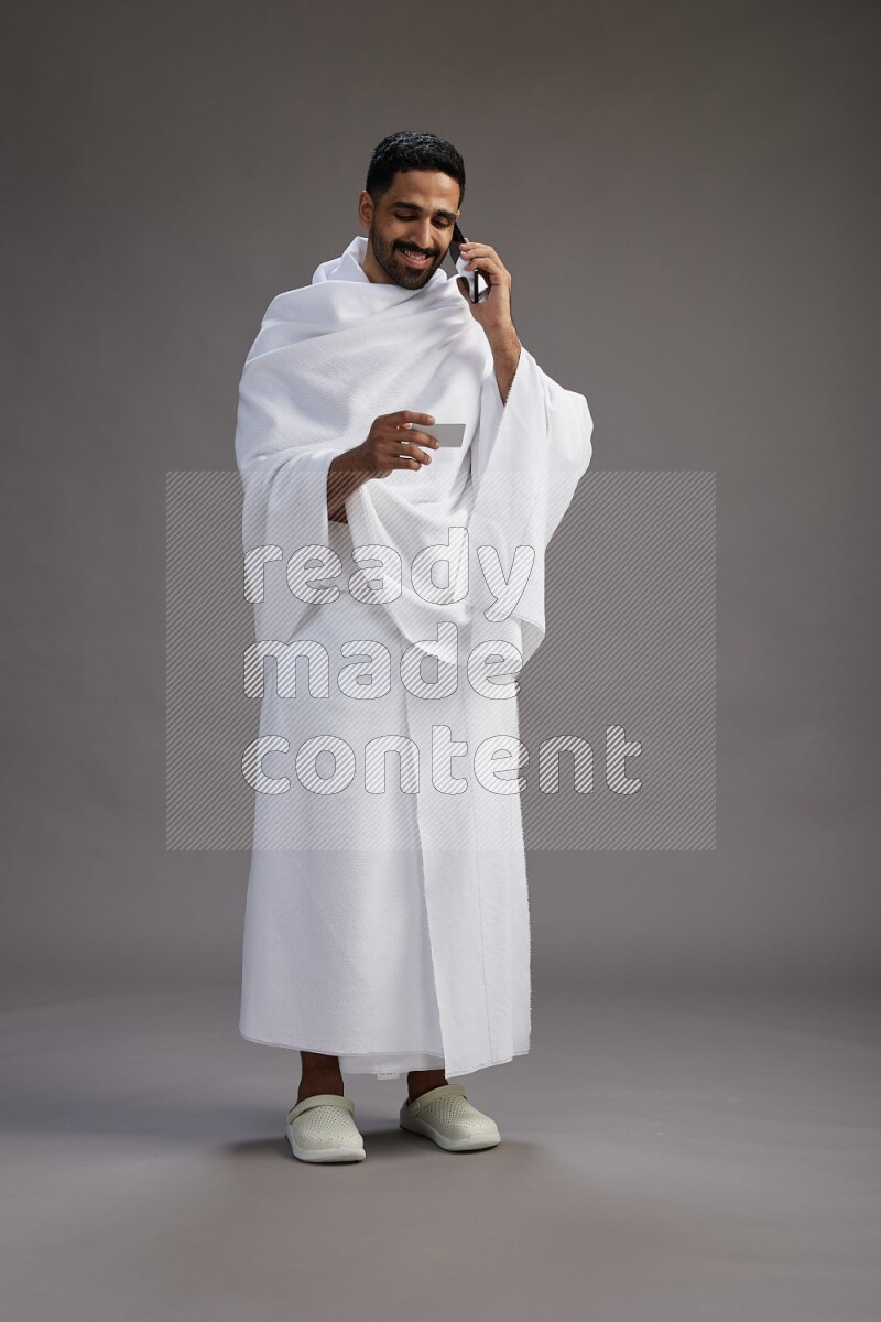A man wearing Ehram Standing holding ATM card on gray background