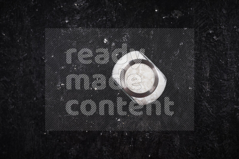 وعاء زجاجي ممتلئ بملح البحر الخشن على خلفية سوداء