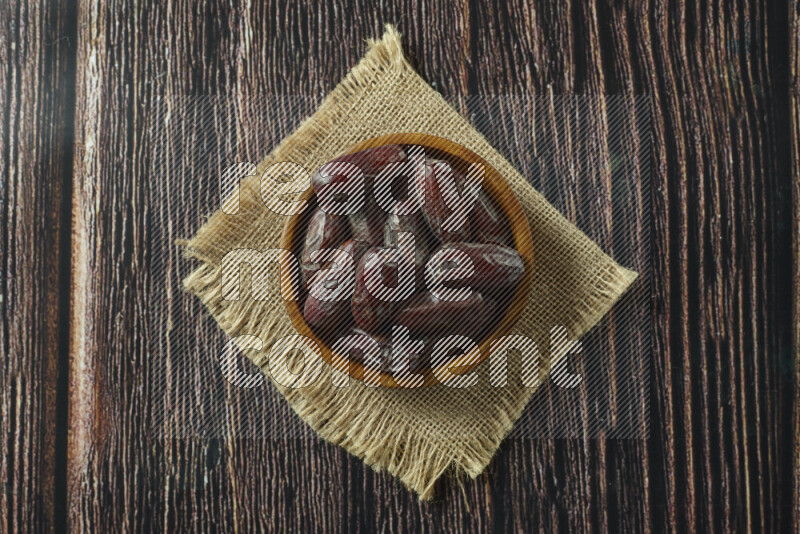 Dates in different bowls (wooden, pottery and glass) on wooden background