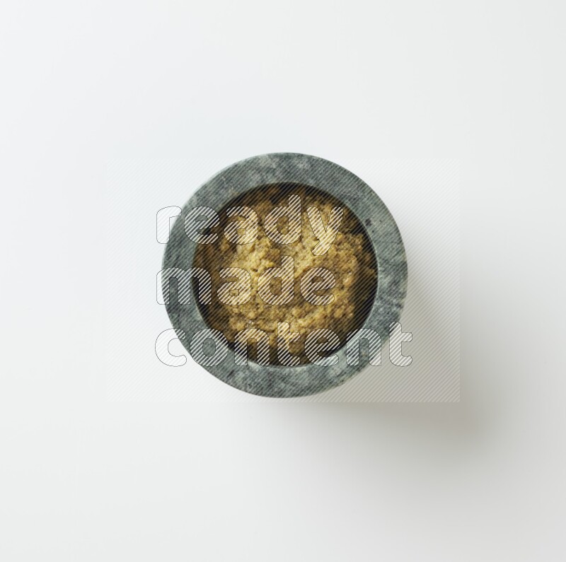 small multi color ceramic round bowl with thick edges, filled with pesto paste on a white counter top