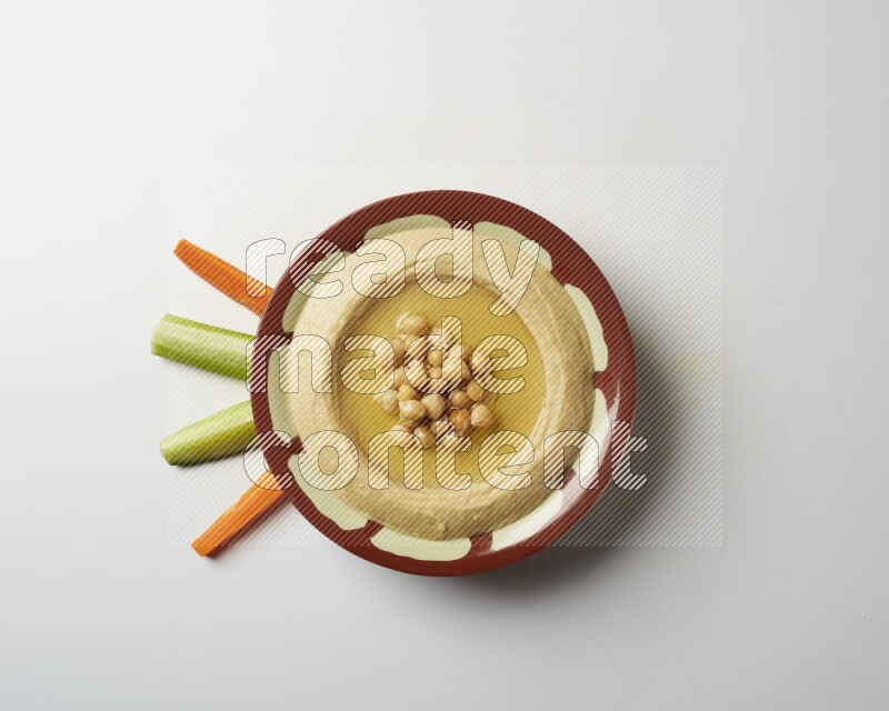 Hummus in a traditional plate garnished with roasted chickpeas  on a white background