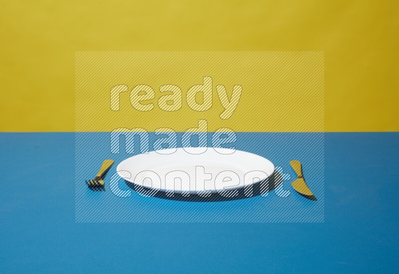 white plate and silverware on yellow and blue background