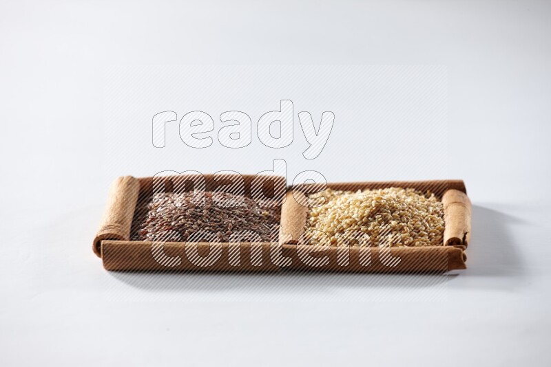 مربعان من أعواد القرفة ممتلئان ببذور الكتان وبذور السمسم علي خلفية بيضاء