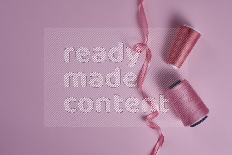 A pink collection of sewing and tailoring tools arranged on a pink background