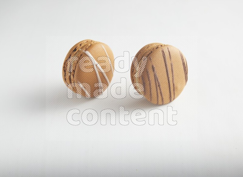 45º Shot of of two assorted Brown Irish Cream, and light brown  Almond Cream macarons on white background