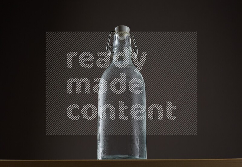 Low angle shot of a bottle of water and ice on grey background