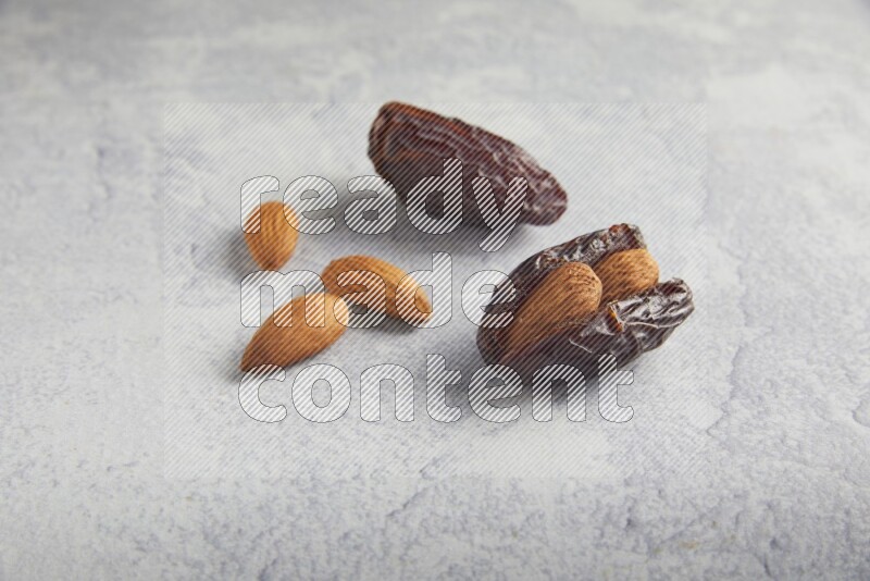 two almond stuffed madjoul dates on a light grey background