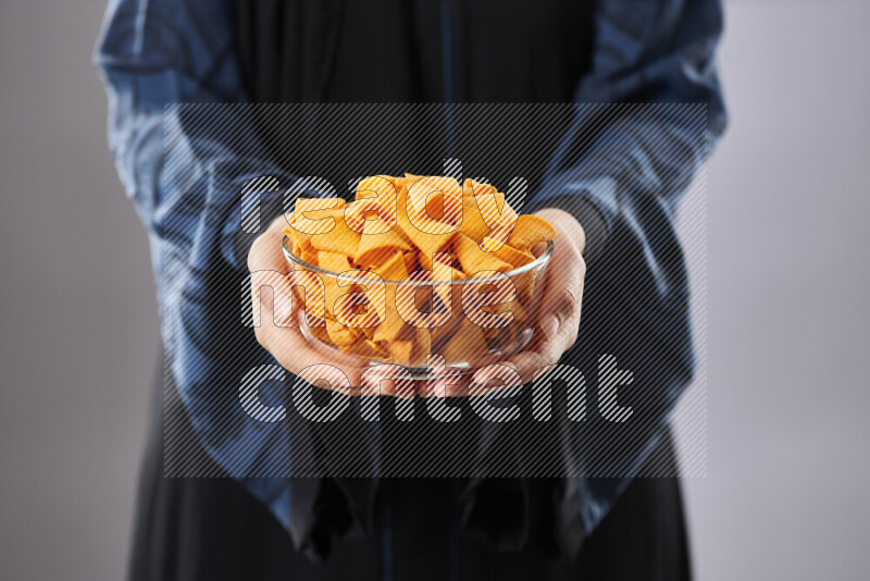 Woman in abaya holding different kinds of snacks in different positions