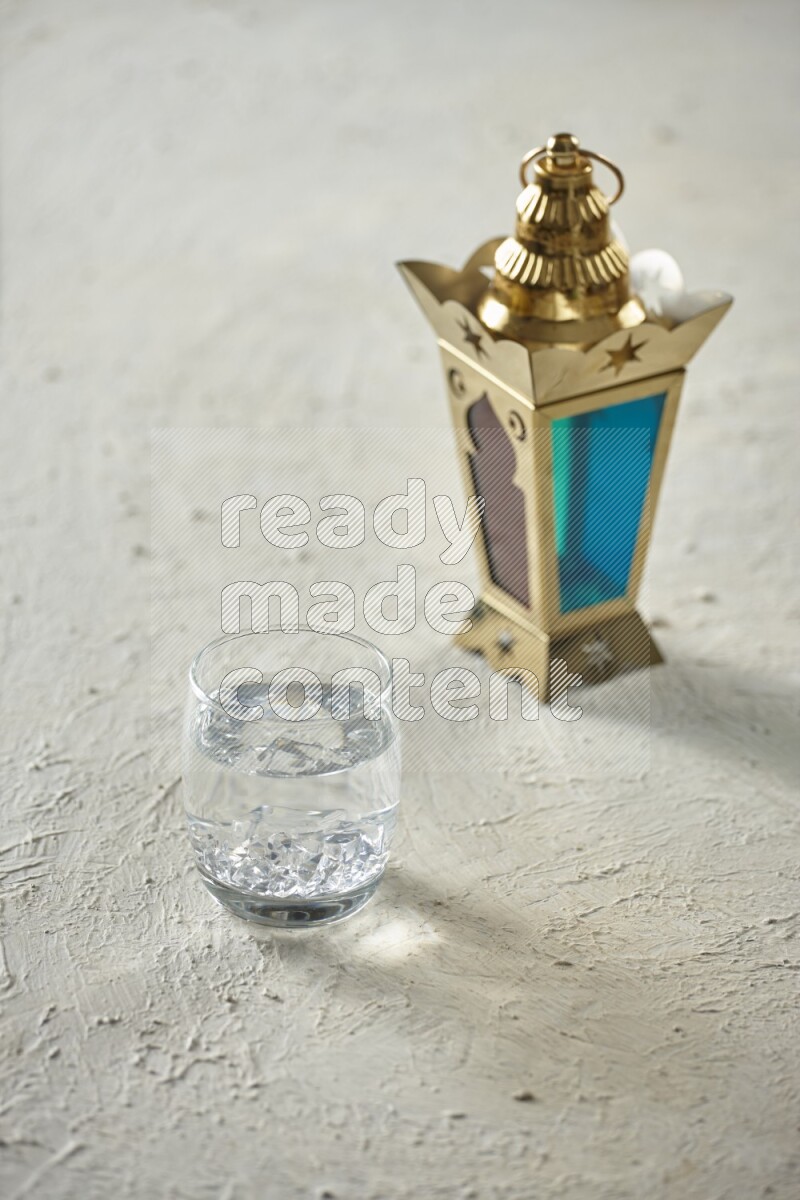 A golden lantern with different drinks, dates, nuts, prayer beads and quran on textured white background