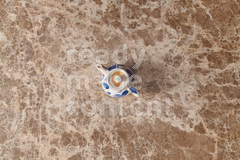 A pottery teapot on beige marble background