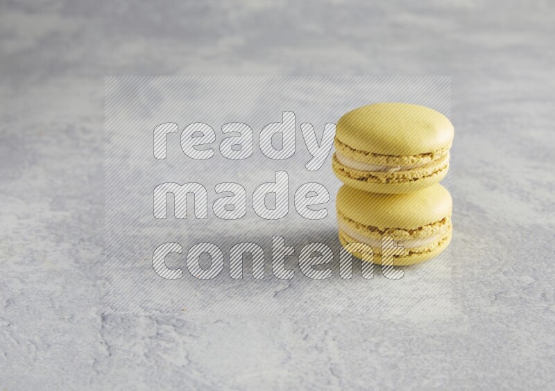 45º Shot of two Yellow Lime macarons  on white  marble background