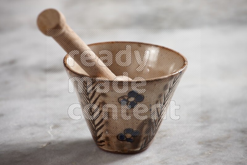 Decorative pottery bowl with wooden honey dipper in it on grey marble background