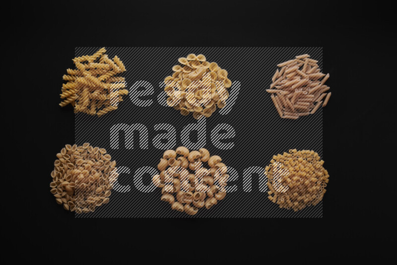 Different pasta types in bunches on black background