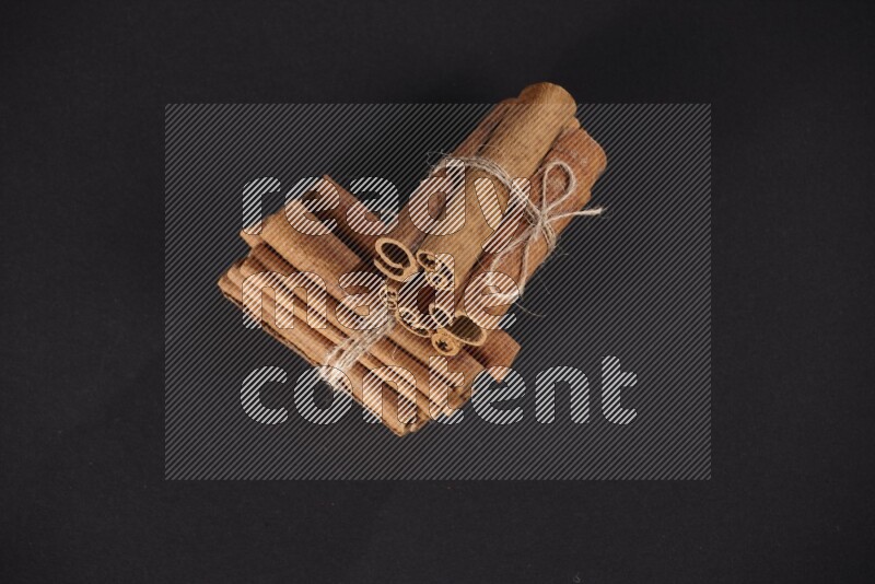 Two bounded stacks of cinnamon sticks on black background