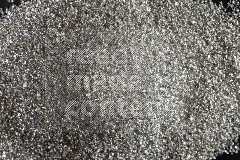 Silver shimmering fragments of glass scattered on a black background