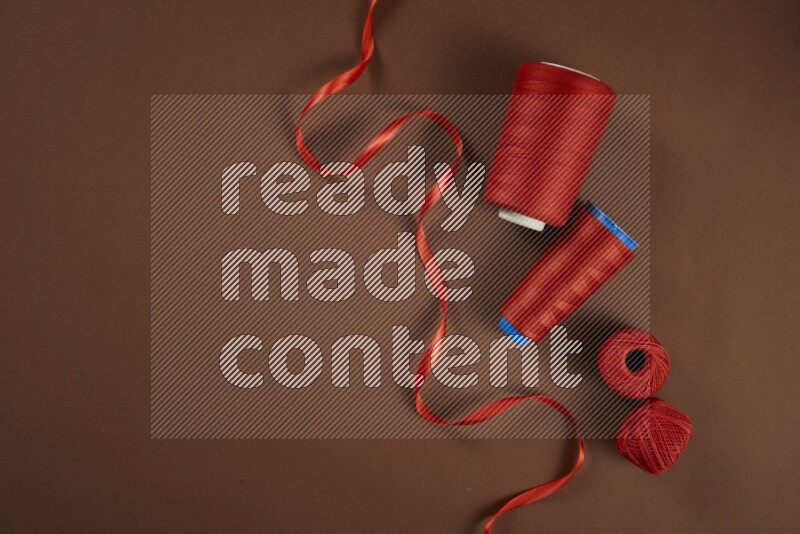 A red collection of sewing and tailoring tools arranged on a brown background
