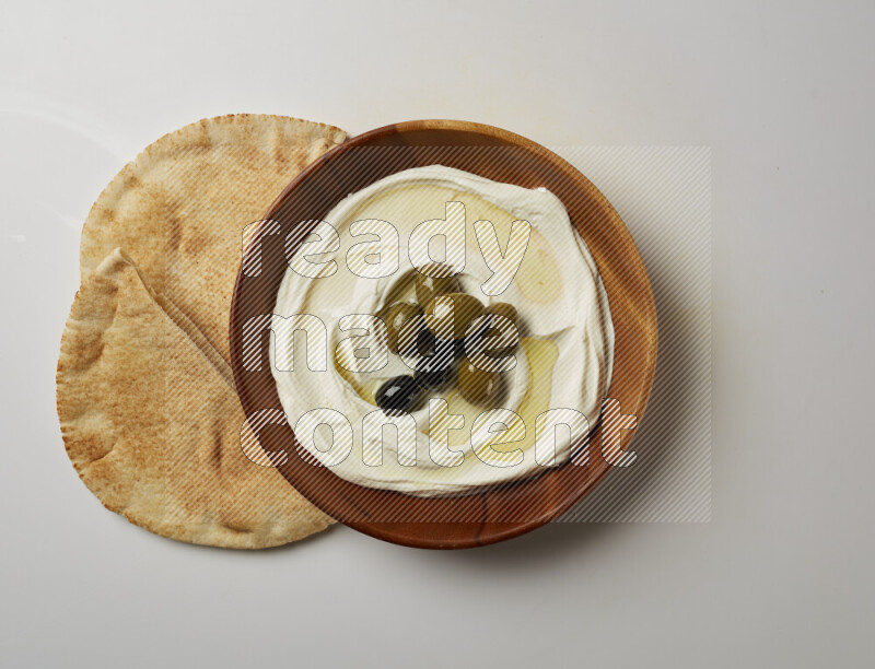 Lebnah garnished with whole olives in a wooden plate on a white background