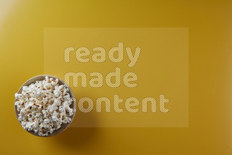 A multicolored ceramic plate full of popcorn on a yellow background in different angles