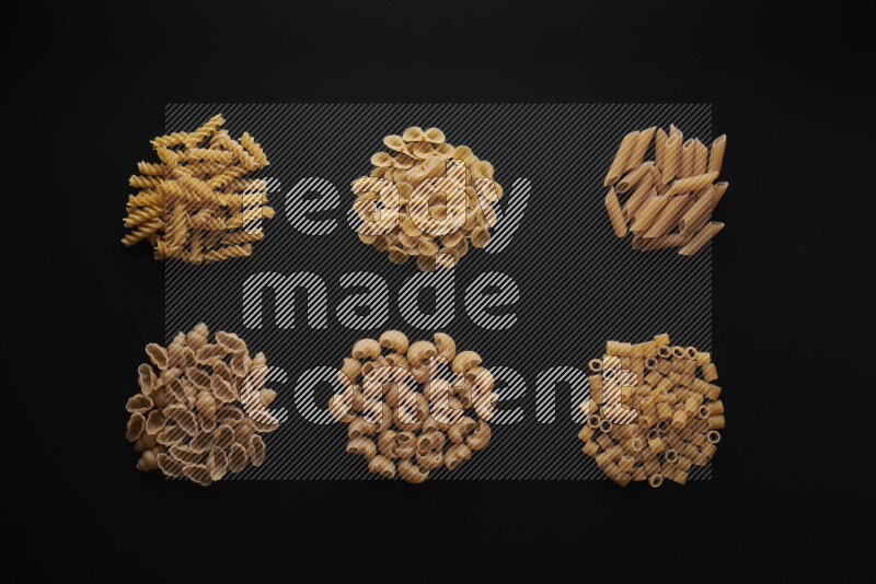 Different pasta types in bunches on black background