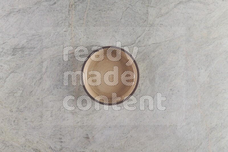 A beige pottery oven bowl on grey marble background