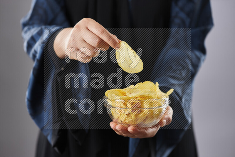 Woman in abaya holding different kinds of snacks in different positions
